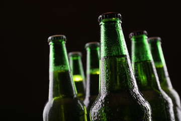 Green glass bottles of beer on dark background, close up
