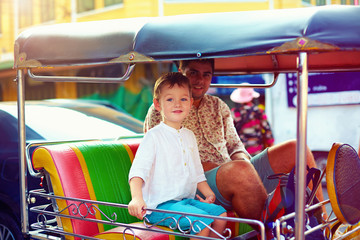 happy tourist family travel through the asian city on tuk-tuk taxi
