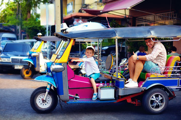 happy tourist family having fun on traditional tuk-tuk taxi in asian city