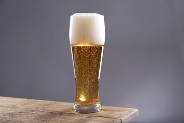 Glass of light beer on grey background