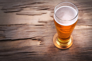 Glass of light beer on wooden background