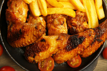 Baked chicken wings with French fries, close up