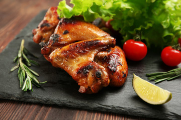 Baked chicken wings with vegetables on slate plate