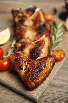 Baked chicken wings with tomatoes and rosemary on cutting board