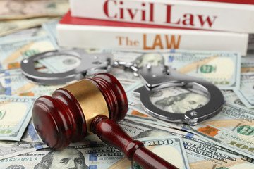 Law gavel with books and handcuffs on dollars background, closeup