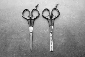 Professional scissors with black handles on a dark grey surface, top view