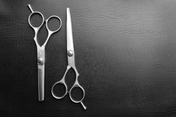 Professional metal scissors on a dark grey surface, top view