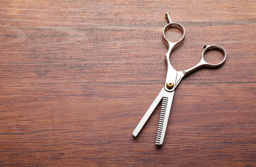 Professional metal scissors lying on the wooden table, close up