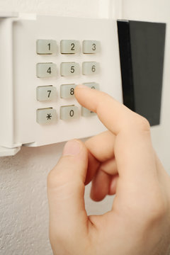 Security alarm keypad with male hand, closeup