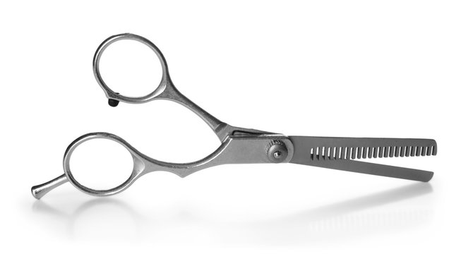 Professional metal scissors in open position isolated on white, close up