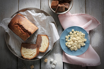 Composition of tasty cake with chocolate morsels and sugar on grey wooden table background, top view