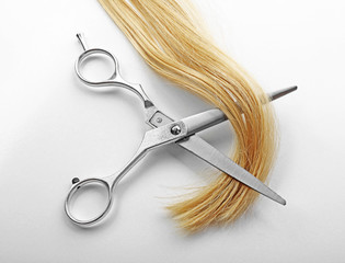 Hairdresser's scissors with strand of blonde hair, isolated on white