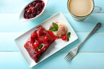 Cherry strudel with mint and cup of coffee on wooden table