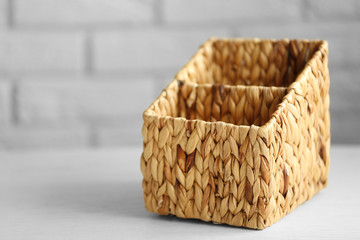 Wicker box on wooden table against brick wall background