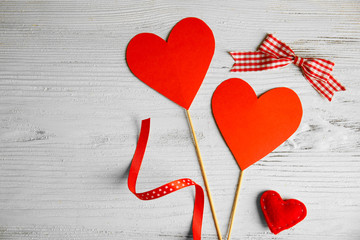 Valentine concept. Two red hearts with sticks and ribbon on wooden table background