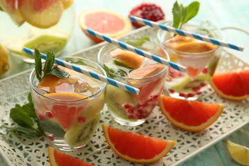 Refreshing cocktails with ice, mint, pomegranate seeds and slices of fruits on a tray