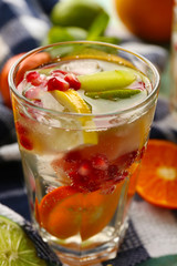 Refreshing cocktail with ice, mint,  pomegranate seeds and slices of fruits