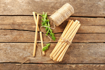 Stack of bread sticks with arugula on wooden table