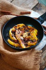 Sliced baked apple with star anise and cinnamon in a pan on wooden table