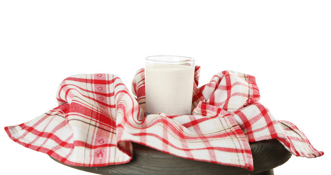 Glass of milk with napkin on wooden stool isolated on white