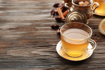 Cup of brewed tea with spices on wooden table