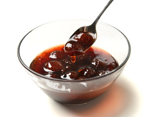 Sweet strawberry jam in the transparent glass bowl with tea spoo