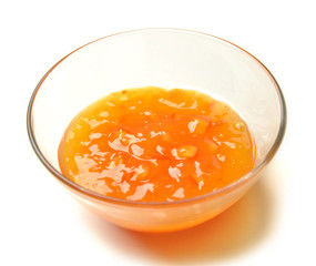 Sweet orange apricot jam in the transparent glass bowl with hone
