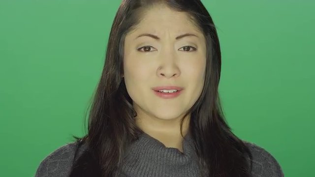 Beautiful young Asian woman sad and angry and crying, on a green screen studio background