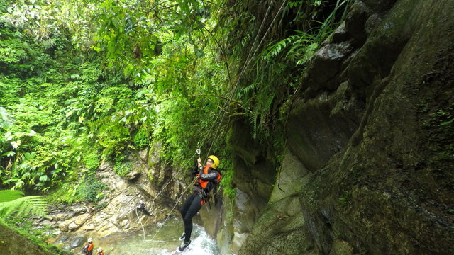 Experience the thrill of young tourist women on a zipline in Ecuadorian canyoning adventure,captured in stunning fixed camera footage at Llanganates National Park. - Powered by Adobe
