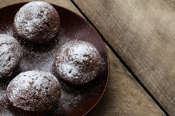 Chocolate muffins icing sugar on a wooden table