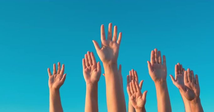 People rasing hands on blue sky background. Voting, democracy or volunteering concept
