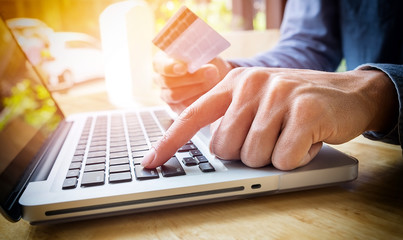 Man holding credit card in hand and entering security code using