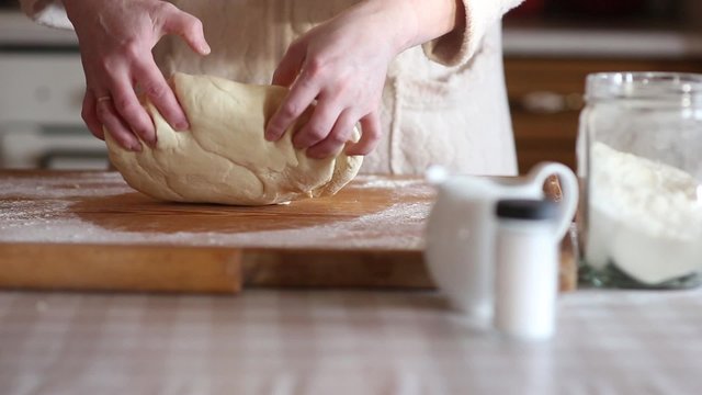 Baker hands kneading dough in flour on table, slow motion