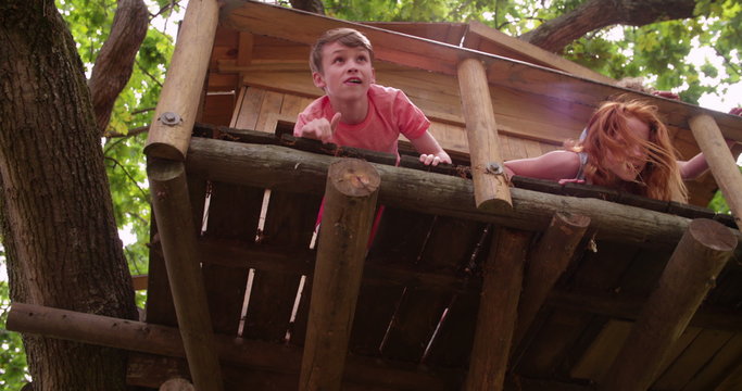 Three young friends playing in a treehouse in summer