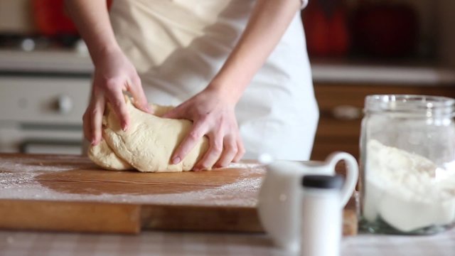 Baker hands kneading dough in flour on table, slow motion