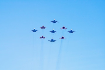 Diamond-shape of 4 Mig-29 The Russian Knights and 5 Su-27 Swifts on blue sky background