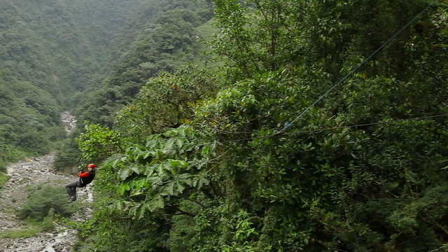 visitor sliding on zip-line at high velocity is stopped down by emergency braking system tracking shot run sport zipline canopi tourist water flow vegetation nature canopy outdoor adventure river ecu