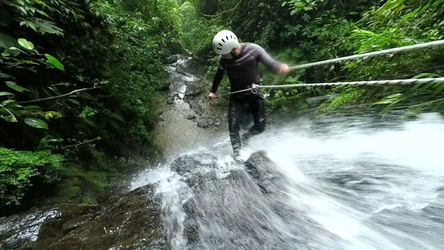 Experience the thrill of canyoning as our expert instructor showcases their rappelling skills near a breathtaking waterfall in mesmerizing slow motion footage.