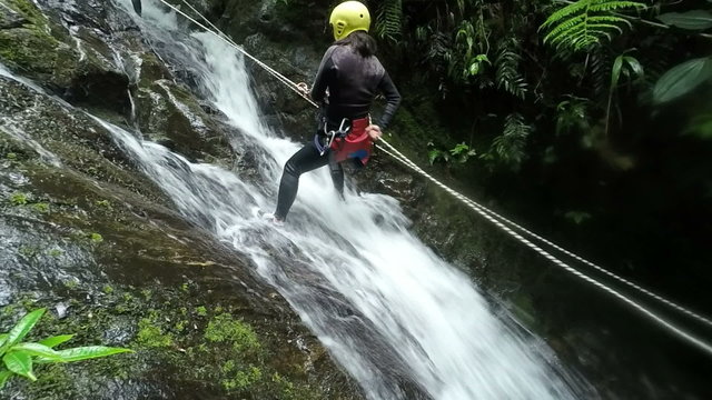 Watch an awe inspiring slow motion footage of a fearless Asiatic girl rappelling down a magnificent waterfall in the enchanting Ecuadorian rainforest.