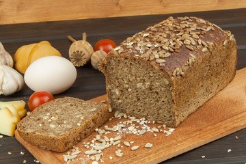 Freshly baked whole wheat bread. Preparing homemade breakfast. Various ingredients for the meal. Sliced bread on cutting board. Advertising on the bakery.
