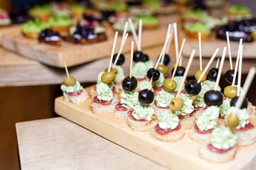 Outdoor kussens Wooden tray of appetizers on pallet coffee table at banquet with jamon, butter cream and olives. Selective focus. © Magryt