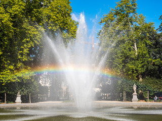Rainbow from artificial fountain in park