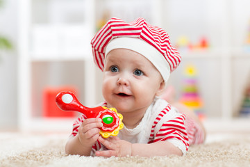 Baby holding a toy lying on carpet in room