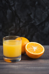 Glass of freshly pressed orange juice with sliced orange half on wooden table