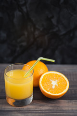 Fototapeta na wymiar Glass of freshly pressed orange juice with sliced orange half on wooden table