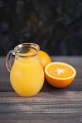 Fototapeta na wymiar Orange juice in clear jar on a wooden background