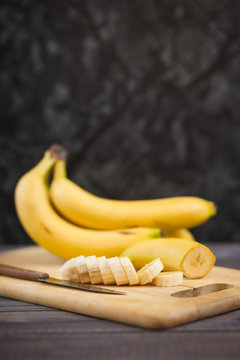 sliced banana with a knife on wooden board