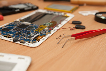 Disassembled computer tablet on wooden background.