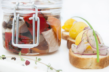 pickled herring in a glass jar with potato canapes