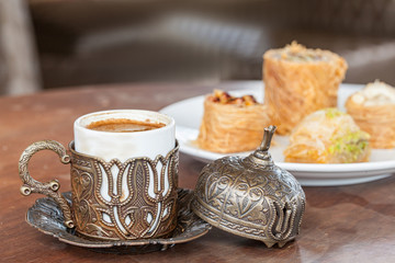 Cup with turkish coffee on the table  with traditional delights on the background. Selective focus.
